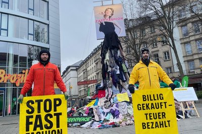 Mitglieder von Greenpeace vor der Skulptur aus Altkleidern.