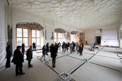 Teilnehmer eines Presserundgangs stehen im Großen Ballsaal im Nordflügel des Dresdner Residenzschlosses und begutachten die Bauarbeiten.