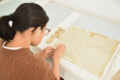 Tingyu Chen aus Taiwan führt eine Trockenreinigung am Niederzwönitzer Notenpapier durch.