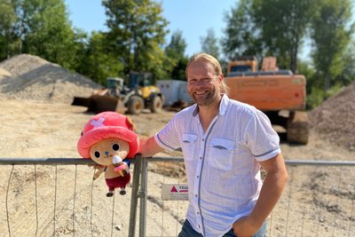 Sakami-Gründer und Geschäftsführer Andreas Ritter mit Chopper, eine Figur aus der Anime-Serie One Piece. Hinter ihm das Baufeld für die neue Halle in Flöha.