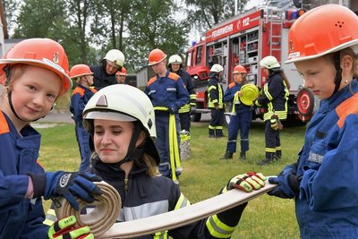Beim ersten Dienst der Freiberger Kinder- und Jugendfeuerwehr in Freiberg nach der Coronapause: Die 16-jährige Gymnasiastin Emely Rausch (Mitte), seit 2016 in der Feuerwehr aktiv, übt mit Paula (links) und Clara das Schlauch-Einrollen. Emely Rausch unterstützt seit März diesen Jahres die Jugendarbeit in der FFW Freiberg. 