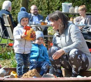 Tagesmutter Elke Schneider (vorn, von rechts) spielt mit Cornelius und Neil. Kultusminister Christian Piwarz (CDU, hinten Mitte) spricht derweil mit Interessenvertretern über die Kinderbetreuung in Sachsen. 