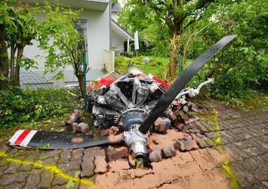 Ein Propeller der Maschine liegt vor einem Wohnhaus.