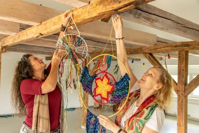 Vereinschefin Ines Schmidt (links) befestigt mit Daniela Sommer-Suppiah aus Hessen im Vereinsraum der ehemaligen Grundschule von Meinersdorf schamanische Kraftgegenstände.