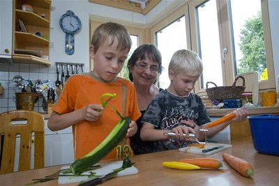 Max und John schnippeln mithilfe von Familienerzieherin Johanna Gemüse für das Abendbrot.