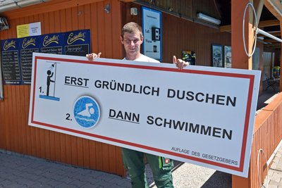 In Falkenau bringt Schwimmmeister-Gehilfe Michael Blosche vorab noch Hinweistafeln an.