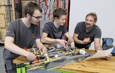 Max Langhammer (l.) und Cedric Csulits lassen sich von Lehrausbilder Ronny Kultscher in der Praxiswerkstatt der Firma Seidel in Lengenfeld die Funktion einer Station für die Trinkwassererwärmung erklären. 