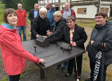 Günter Eckardt vom Verein Silberschmelzhütte Sankt Georgen Schneeberg(2. v. l.) erklärt Birgit Kaiser, Gabriela Blechschmidt und der Vorsitzenden Renate Müller, alle vom Verein Blinder und Sehbehinderter Aue-Schwarzenberg, sowie Helga Dittrich, der Senioren- und Behindertenbeauftragten des Landkreises (v. l.) , das Modell der Silberschmelzhütte. 