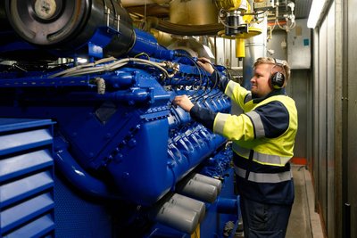 EVR-Mitarbeiter Eric Bott am Motor des Heizkraftwerkes, das mit Biomethangas betrieben wird.