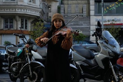 Eine Straßenmusikerin spielt Geige auf einem Bürgersteig im Norden Teherans.