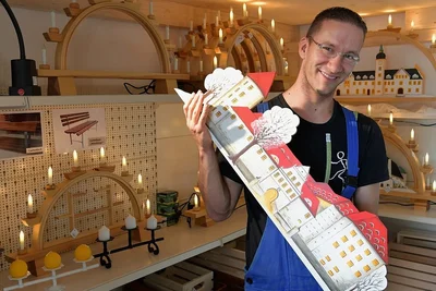 Auch Deko-Artikel bis hin zum Weihnachtsschmuck werden in der Werkstatt gefertigt. Mitarbeiter Roberto Gazso zeigt das Freiberger Schloss - eines der Schwibbogenmotive. 