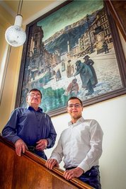 Volkmar Klausnitzer und Dr. Armin Klausnitzer (von links) vor dem historischen Bild im Verwaltungssitz in Oederan: Darauf ist Firmengründer Magnus Baumann verewigt, hier zu sehen beim Begutachten von Gurken.