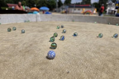 Auf den Kindertischen wird mit Stoffunterlage und Glasmurmeln gespielt.