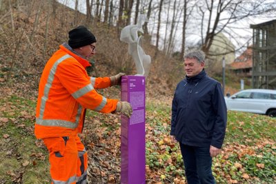 Bauhof-Mitarbeiter (im Bild Andreas Horbach und Bürgermeister Jens Schmidt) haben am Donnerstag die Purple-Path-Skulptur „Inside“ (im Hintergrund) mit der Info-Stele aufgestellt.