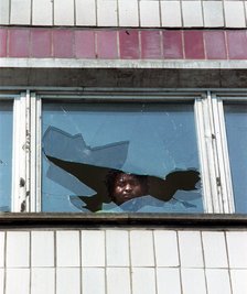 Ein Mann blickt am Tag nach den ausländerfeindlichen Übergriffen durch die eingeworfene Scheibe eines Wohnheims.