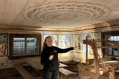 Beeindruckende Deckenmalerei trifft bäuerliche Gemütlichkeit: Museumsführerin Johanna Nyström zeigt die Wohnstube eines Hauses, das am Original-Standort abgebaut und im Dalarnas Museum in Falun neu aufgebaut wurde.
