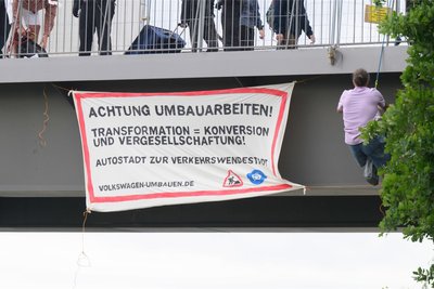 Konnten dieses Jahr die Hauptversammlung nicht stören, weil sie nur als Online-Veranstaltung abgehalten wurde. Aktivisten befestigen an der Brücke zur Autostadt am VW-Werk Wolfsburg ein Protestplakat.