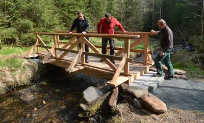 Bürgermeister Ralf Kretzschmann und die Bauhof-Mitarbeiter Tilo Möckel und Timo Pöhler schauen sich die neue Fußgängerbrücke an. 