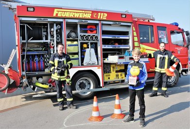 Kamerad Sven Stenker (l.) und der stellvertretende  Wehrleiter Bjön Bork (r.) von der Freiwilligen Feuerwehr Falkenau  zeigten dem elfjährigen Tyler Tanneberger (M.) das Feuerwehrdepot und  die Fahrzeuge.