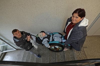 Wenn mal wieder der Fahrstuhl kaputt ist. Marie und Ronny Stegbauer tragen den Rollstuhl mit Tyger-Noel die Treppen hoch in den 5. Stock ihres Neuplanitzer Wohnhauses.