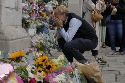 Von Emotionen überwältigt, hockt ein Trauernder am Tor des Buckingham Palastes.  