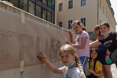 Die graue Mauer vor dem Bildungszentrum "Adam Ries" soll ein farbenfroher Blickfang werden. Schülerinnen der Klasse 4b gestalten ihn innerhalb eines Ganztagesangebotes unter Leitung von Sabine Sachs. 