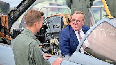 Ein Bundeswehr-Soldat zeigt dem Minister auf der ILA einen Tornado-Simulator. 