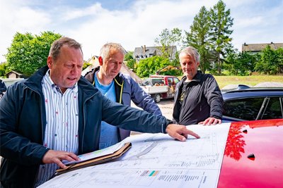 Steven Dummis vom Ingenieurbüro Ökoplan (l.), Enrico Baldauf, stellvertretender Amtsleiter Abwasserentsorgung und Tiefbau, sowie Marcel Pügner, Geschäftsführer der Firma TBS Tiefbau und Baumaschinen (r.), mit einer Karte des neuen Wohngebietes.