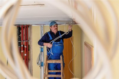 Elektriker Andreas Küger, Mitarbeiter der Firma ETM Elektrotechnik Mehnert aus Rochlitz, zieht Kabel für die Deckenbeleuchtung.