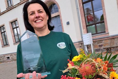 Sandy Vogel freut sich über den Generationen-Award, der demnächst einen Ehrenplatz in der ehemaligen Schule Grünberg (im Hintergrund) erhält.
