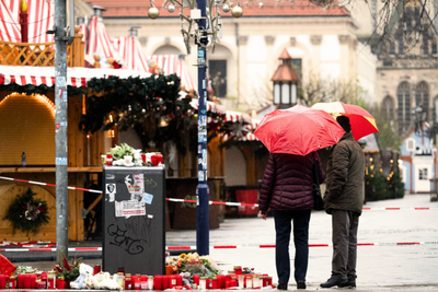 Zwei Passanten mit Regenschirmen stehen vor dem Weihnachtsmarkt. Am 20. Dezember 2024 ist auf dem Weihnachtsmarkt in Magdeburg ein Autofahrer in eine Menschengruppe gefahren.