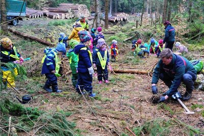 Die Mädchen und Jungen von der Zwotaer Waldwichtel-Kita halfen bei der Pflanzaktion im Glasbachtal mit. PaulPietrock vom Sachsenforst (rechts) zeigte ihnen, wie die Bergahorn-Setzlinge fachgerecht in den Waldboden gebracht werden. Danach probierten sie es dann selbst. 
