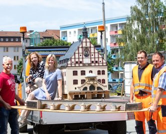 Die Mitarbeiter des städtischen Bauhofs und des Dachverbandes Stadtmarketing Plauen mit einem der Festwagen. Darauf zu sehen: das historische Rathaus in Miniatur aus der Schauanlage in Adorf. 