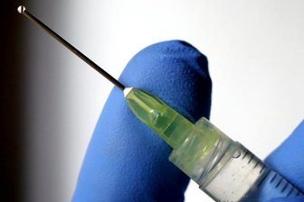 Eine Flüssigkeit tropft aus der Kanüle einer Spritze.