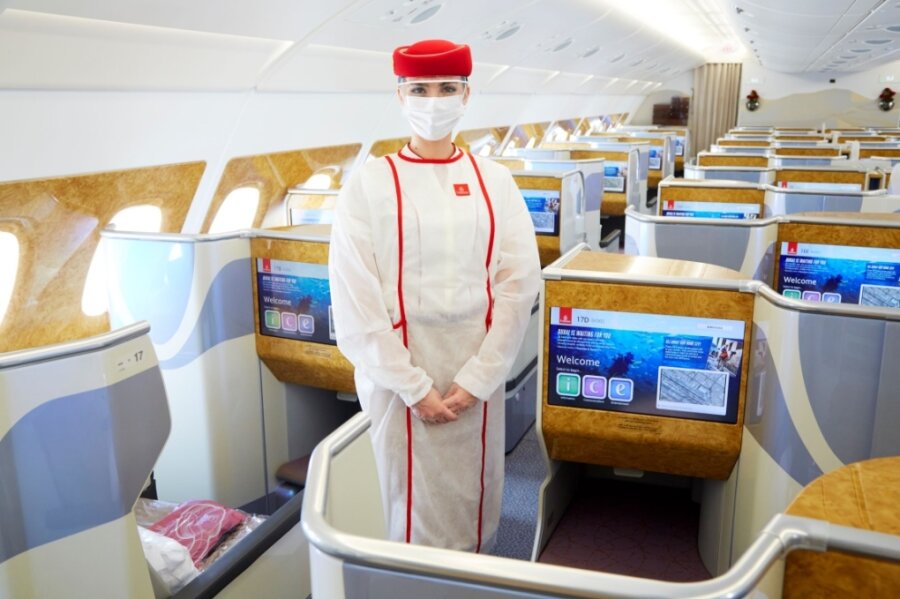Abheben zum Urlaub in Corona-Zeiten - Sicherheit geht vor: Die Flugbegleiterin trägt über ihrer Uniform persönliche Schutzausrüstung. 