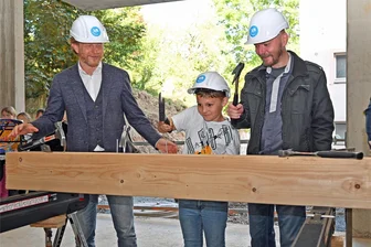 Adelsberger steigen ihrer Grundschule aufs Dach: Grundschule soll 2024 fertig sein - Zum Richtfest wird gehämmert: Baubürgermeister Michael Stötzer, Grundschüler Florian und Schulleiter Lars Ritter (v. l.) greifen zum Werkzeug.