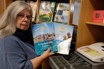 Adventsmarkt in Reichenbach abgesagt: "Eine ganz schwierige Situation" - Silke Baumann mit neuen Urlaubskatalogen und leerer Kasse in ihrem geschlossenen Reisebüro.