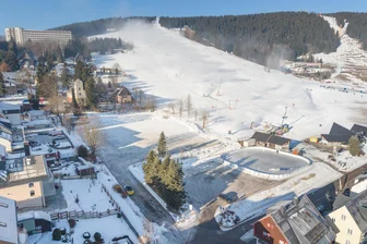 Ärger am Fichtelberg: Berliner eröffnen Parkplatz am Skihang – „Widerrechtlich“, sagt der Bürgermeister - Das Foto zeigt vorn die Eisbahn und den städtischen Parkplatz. Links daneben die Zufahrt zu der Fläche, auf der einst der „Alte Club“ stand.