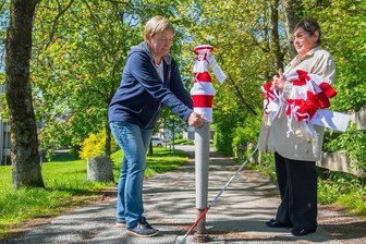 Aktion für Menschen mit Sehschwäche: Poller in Schneeberg und Aue-Bad Schlema bekommen rote Mützen - Gabriela Blechschmidt und Renate Müller (rechts) ziehen einem Poller eine rot-weiß geringelte Mütze an. 