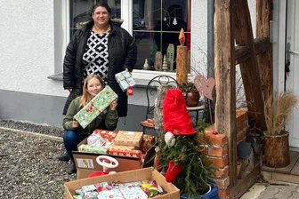Aktion in Blankenhain: Spielzeug verschenken - Manuela Held und Tochter Stina vor einer Kiste voller Weihnachtspäckchen.
