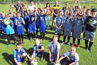Alle Kicker auf dem Rasen - Claudia Linke (hinten Mitte) freut sich mit Trainern und jungen Spielern, dass das Training endlich wieder möglich ist.