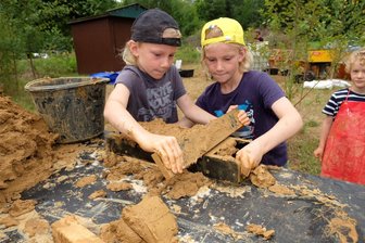 An der Göltzschtalbrücke entstehen 500 Ziegel wie in vorindustrieller Zeit - Ziegelherstellung wie in vorindustrieller Zeit: Milan und Anton Leonhardt aus Plohn haben die Lehm-Sand-Mischung in eine Ziegelform gegeben und ziehen mit einem Brett die überschüssige Masse ab.