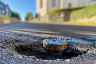 An Schachtdeckeln bröckelt der Asphalt: Crandorfer Straße in Erla wird in den Herbstferien Baustelle - Auf der Crandorfer Straße in Erla wimmelt es von blauen Markierungen. Der Asphalt an Schachtdeckeln ist ausgebrochen.
