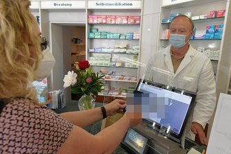 Anlaufprobleme: Wie es mit dem digitalen Impfpass in Mittelsachsen klappt - Apotheker Thomas Paul stellt in der "Löwenapotheke" an der Burgstraße in Freiberg Grit Baldauf, Regionalleiterin der "Freien Presse" in Mittelsachsen, einen digitalen Impfpass aus. Am Montagmittag war der Ansturm noch nicht allzu groß.