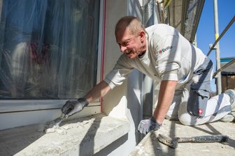 Ansage an Leerstand: Was diese Stadt im Vogtland aus ihren grauen Blocks macht - Die Blöcke an der Lindenstraße werden saniert. Firmen wie die Malerfirma Wolf aus Lengenfeld partizipieren von den Aufträgen. Ronny Petzold bereitet die Fensterflächen auf.