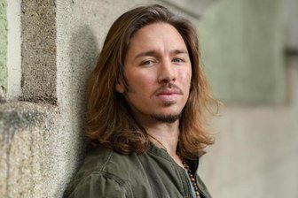Der Sänger Gil Ofarim lehnt an einer Hauswand.