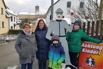Anwohner im Vogtland verärgert über geklauten Holzpolizisten: Dieses Problem steckt dahinter - Ein Holzpolizist ist noch da, einer wurde gestohlen: Die Anwohner der Burgstraße sind darüber verärgert. Von links: Anne Lenhart, Anne-Katrin Grimm, Max Lenhart und Silas Grimm.