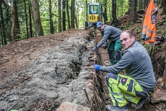 Arbeiten dauern deutlich länger: Beliebter Wanderweg im Erzgebirge ist frühestens Ende 2024 wieder komplett begehbar - Stein für Stein: Stefan Körner (vorn) und Swen Riedel errichten in Handarbeit die Natursteinmauer, die in Richtung Schwarzwassertal als Uferbefestigung des Grünen Grabens dient.