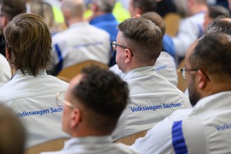 Arbeitsordnung angepasst: VW-Werker in Zwickau dürfen jetzt auch in Arbeitskleidung zur Schicht kommen - Mitarbeiter im Fahrzeugwerk Zwickau in Arbeitskleidung bei einer Betriebsversammlung.