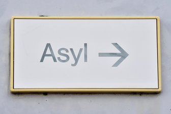 Arbeitspflicht für Asylbewerber: Zwickauer Kreistag lehnt AfD-Vorstoß wegen zu hohen Aufwands ab - Ein Schild hängt in einer Erstaufnahmeeinrichtung an einer Wand. Im Landkreis Zwickau werden Asylbewerber bislang kaum zu gemeinnützigen Arbeiten herangezogen.